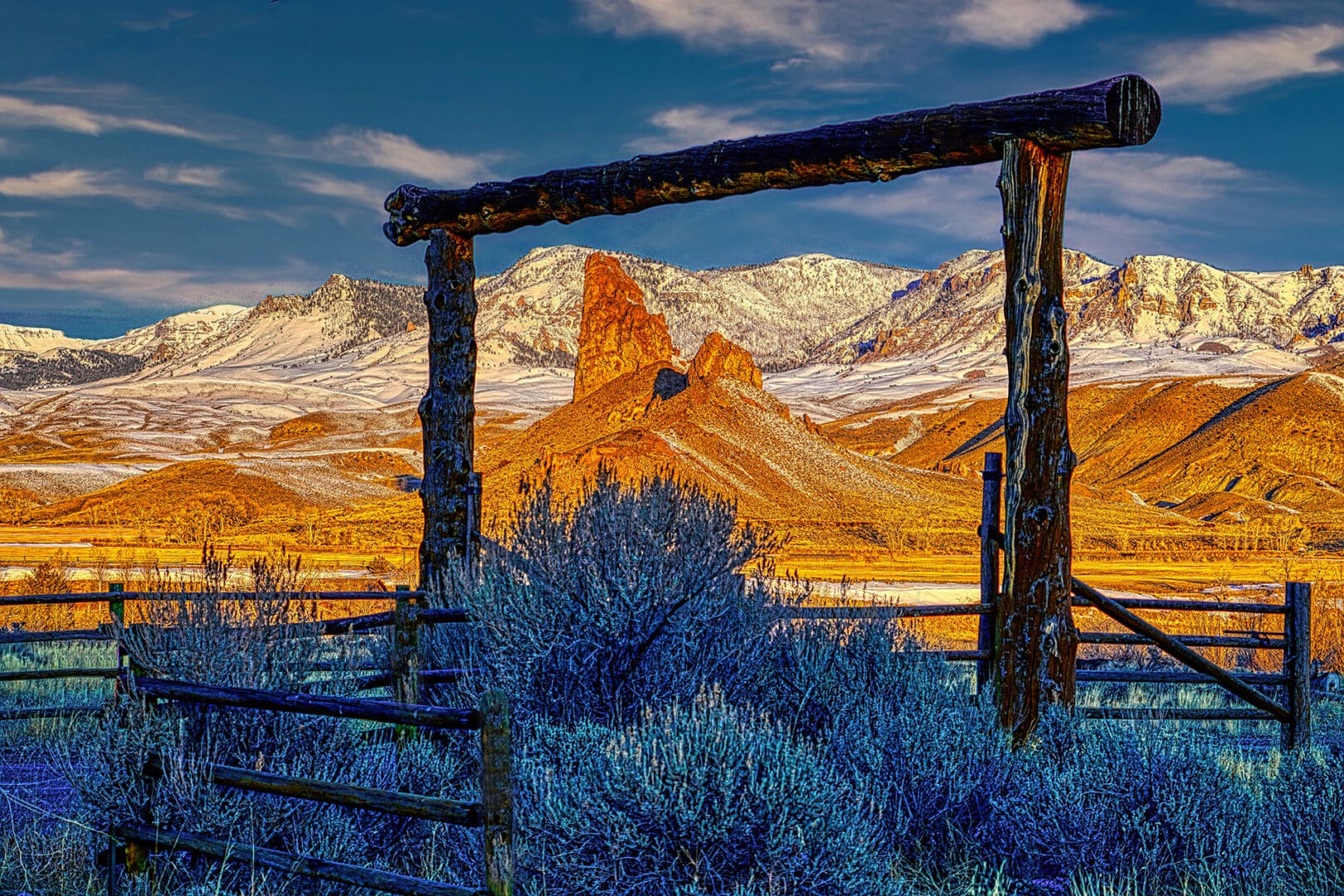 A wooden fence in the middle of a field with mountains in the background.