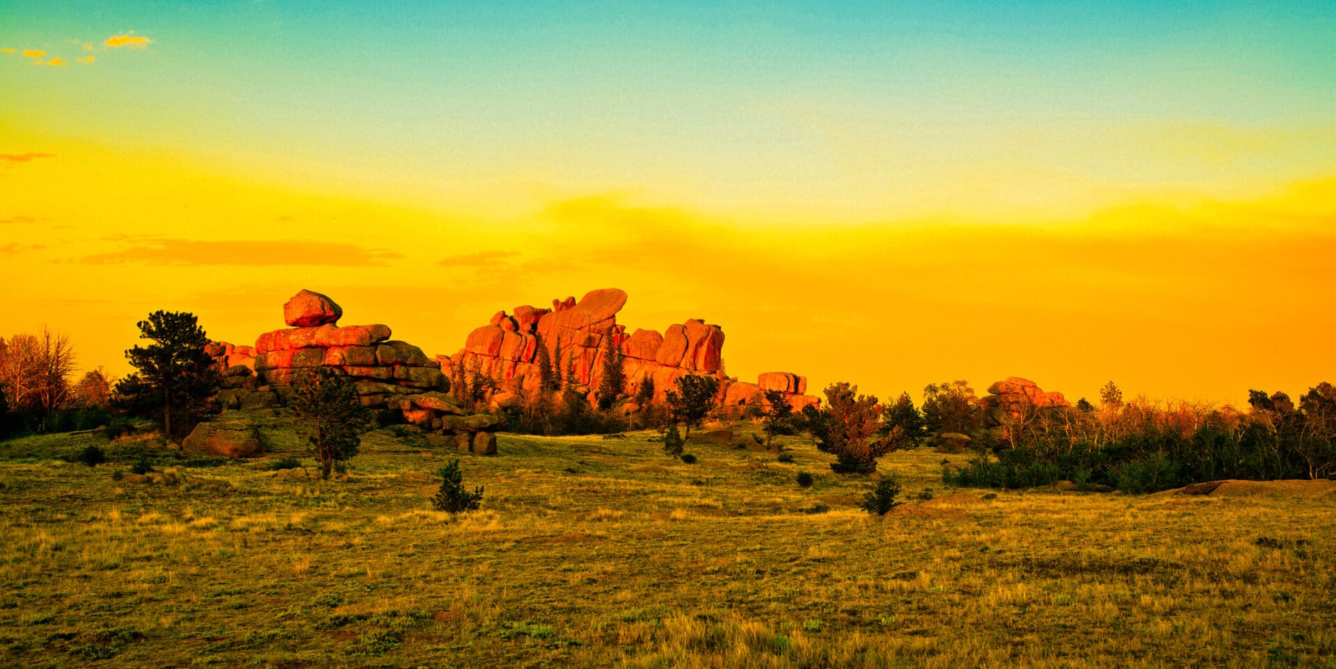 A rock formation in the middle of a grassy field.