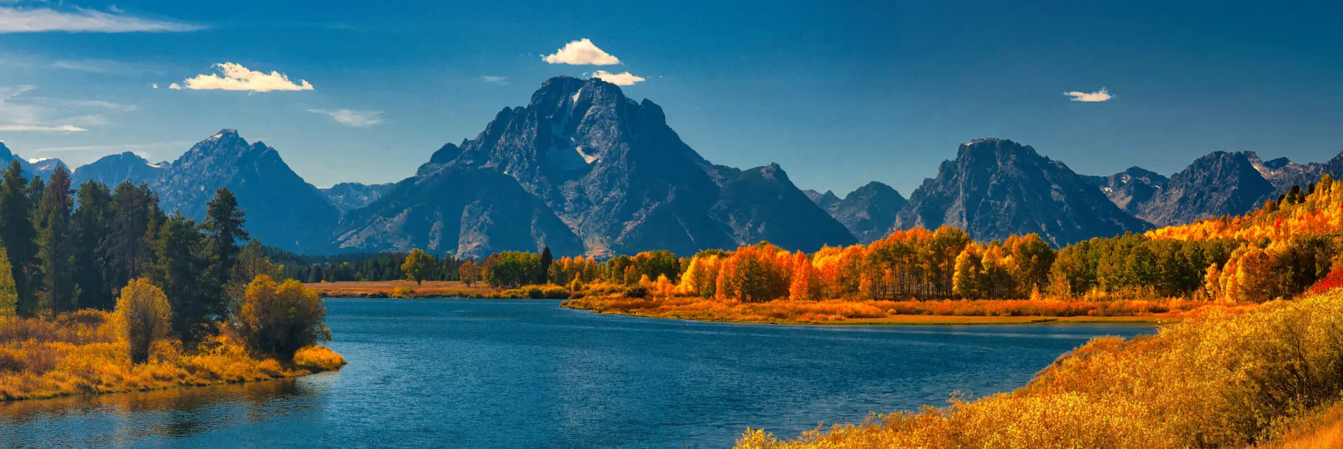 A river surrounded by mountains and trees in autumn.